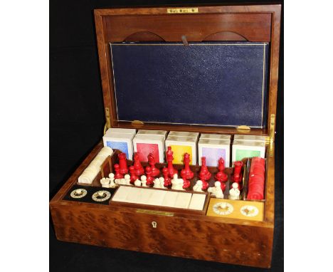 A mid 20th Century amboyna and ivory inlaid games compendium, the lid opening to reveal a fitted interior comprising a carved