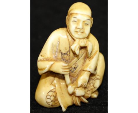 A 19th Century Japanese Meiji Period carved ivory netsuke in the form of a peasant with headscarf, in seated position working