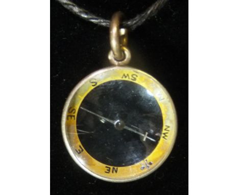 A yellow metal cased compass of simple form, 2 cm diameter approx