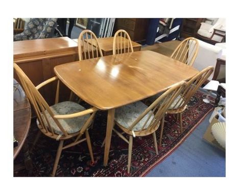 A light Ercol dining table, together with six stick back chairs two being carvers and a sideboard having three cupboard doors