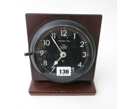 A military ships bulkhead clock by Elliott, mounted as a mantel clock.  The 5 black dial with white numerals and hands barrin