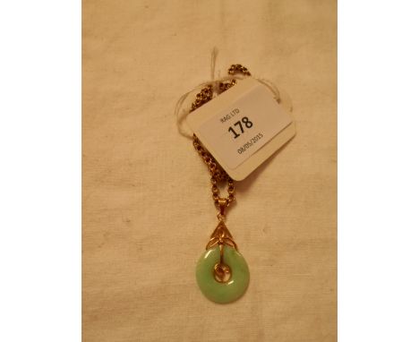 A 14k gold and jade disc pendant and chain