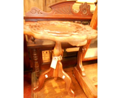 A mid 20th C mahogany wine table the shaped top carved with lily pad and blossoms, raised on a tripod base bearing a label ha