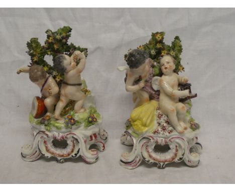 A pair of late 18th/early 19th Century Bow porcelain figures of cherub musicians amid floral branches on scroll bases, 9" hig