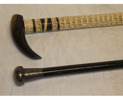 An unusual horn mounted vertebrae walking stick and a gentlemans ebony walking cane with silver mounted top (2)