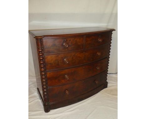 A Victorian figured mahogany bow-front chest of two short and three long drawers with turned handles flanked by spiral column