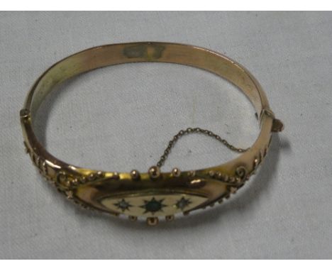 A 9ct gold bangle with ornate raised decoration set three stones