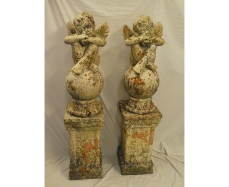 A pair of old painted terracotta garden figures of cherubs on rectangular plinth columns 52" high overall