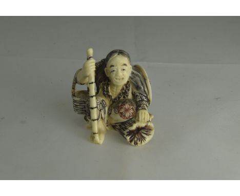 Japanese - Early 20th Century Carved Ivory Netsuke of a Crouching Figure Holding a Staff. 1.75 Inches High. All Aspects of Co