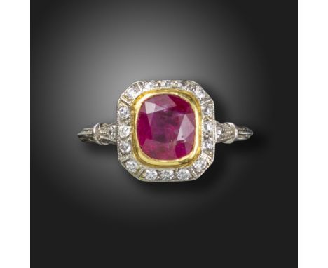 A ruby and diamond cluster ring, set with a cushion-shaped ruby within a surround of old circular-cut diamonds, with further 