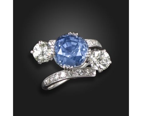 A sapphire and diamond three-stone ring, the cushion-shaped sapphire weighs 6.81cts, with an old circular-cut diamond to each