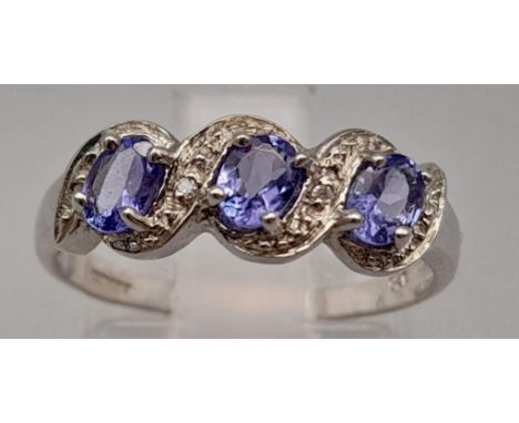 A 9K White Gold Three Stone Amethyst and White Stone Ring. Size M. 1.75g. 