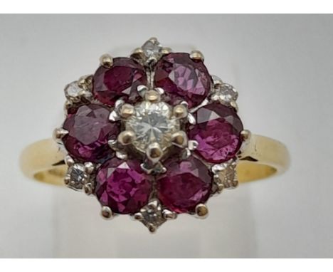 An 18k Yellow Gold Ruby and Diamond Ring. Central diamond surrounded by a halo of rubies. 3.71g 