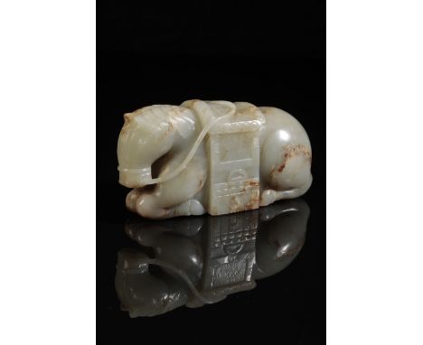 A CHINESE MOTTLED CELADON JADE KNEELING HORSE wearing an elaborate saddle, with a finely-carved mane and a well-defined rein,