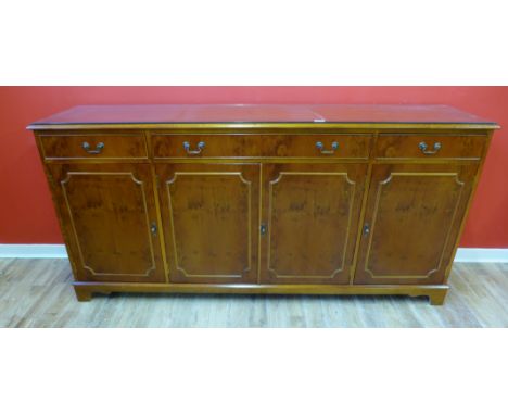 A yew wood sideboard having a moulded top above three long drawers and cabinets raised on bracket feet, 183 x 89cm