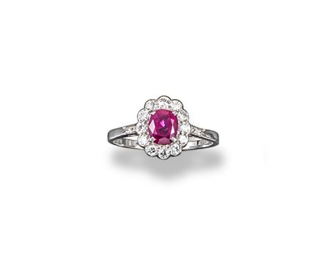 A ruby and diamond cluster ring, the oval-shaped ruby is set within a surround of diamonds with four small shoulder diamonds 
