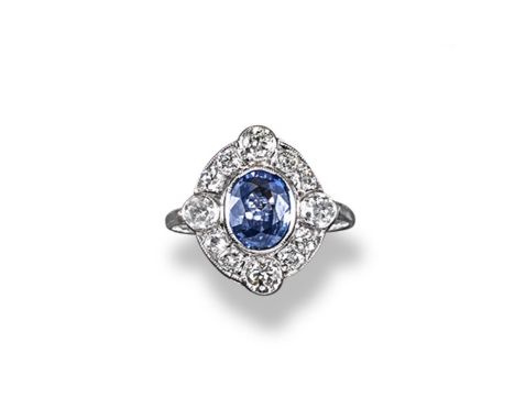 A sapphire and diamond cluster ring, the oval shaped sapphire is set within a surround of graduated circular cut diamonds in 