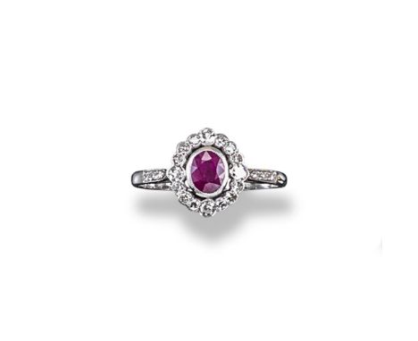 A ruby and diamond cluster ring, the oval-shaped ruby is set within a surround of graduated circular cut diamonds in white go