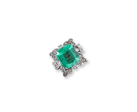 An emerald and diamond cluster ring, the emerald cut emerald weighs approximately 7.00cts and is set within a surround of cir