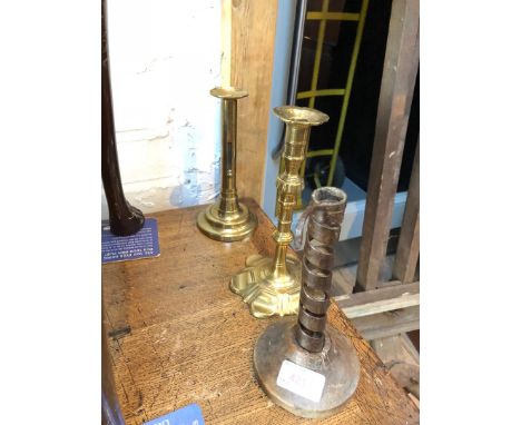 A group of three antique candlesticks comprising an 18th Century hog scraper, a petal based brass candlestick and an ejector 