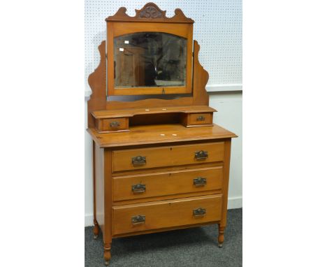 A satinwood dressing table, shaped and carved pediment to arched mirror, two short drawers and shelf to superstructure, three