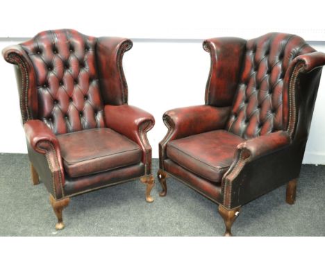 A pair of leather wingback armchairs, button upholstered 