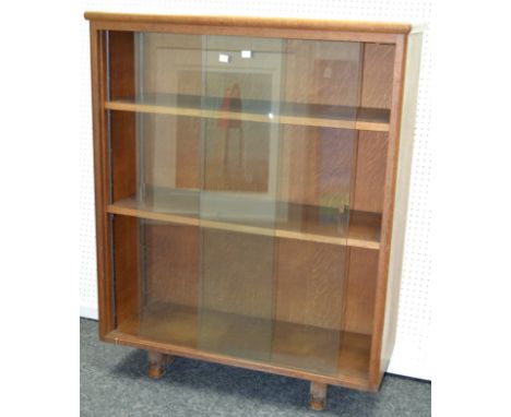A retro light oak bookcase with sliding glass doors.107cm high x 86cm wide x 35cm deep.