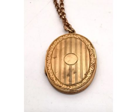 A 9ct yellow gold engraved locket and rolo link chain. The front and back of the locket engraved with a linear design with la