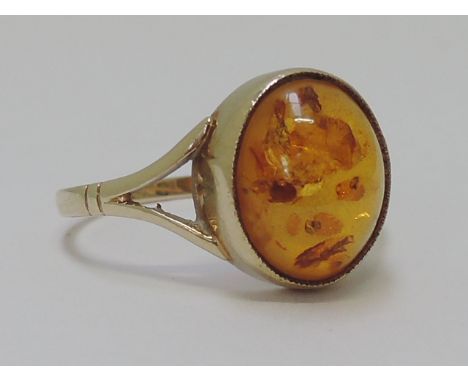 A ladies dress ring having a Baltic Amber cabouchon stone to open shoulders on a 9ct gold loop 