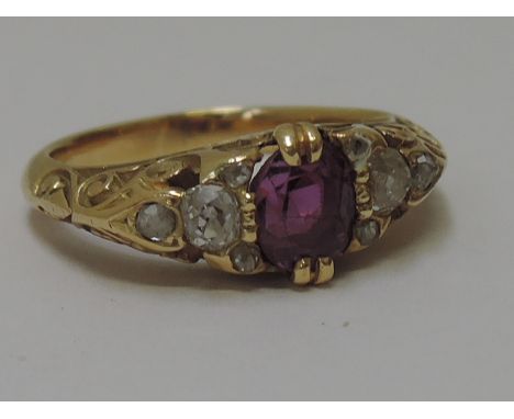 A ladies dress ring having a central oval ruby within diamond surround in a moulded gallery mount on a yellow metal loop, no 