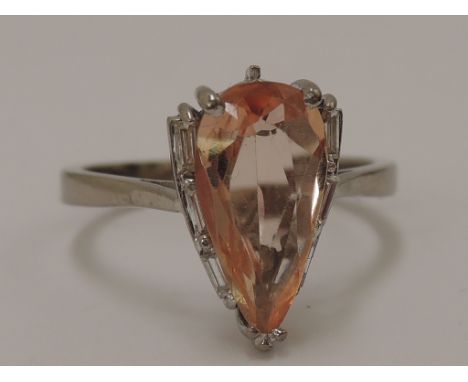 A ladies dress ring having a tear drop shaped Brazilian pink topaz stone with three small  baguette cut diamonds to each side