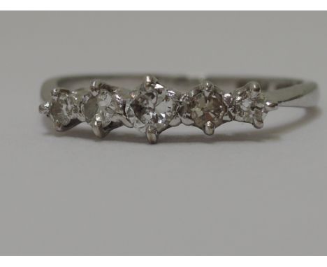 A ladies dress ring having five graduated diamonds in a raised claw mount on a white metal loop stamped 18ct & Plat. (with co