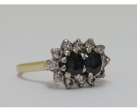 A ladies dress ring having a double sapphire and diamond cluster in a raised basket mount on an 18ct gold loop