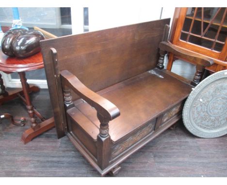 A late 20th century oak monk's bench of typical design on shaped feet