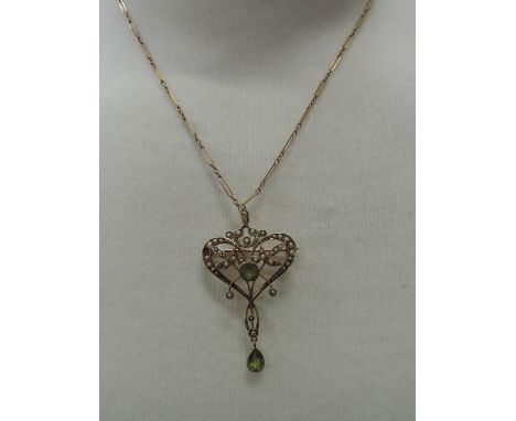An Edwardian yellow metal pendant stamped 9ct having a central peridot within seed pearl foliate surround with further perido