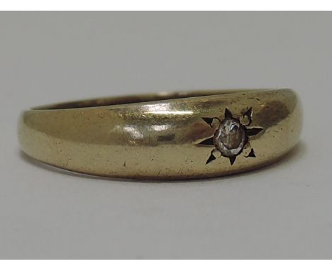 A ladies 9ct gold band ring having an inset diamond in star burst setting 