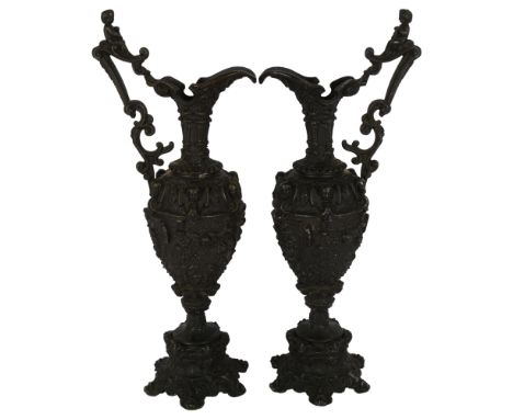 A pair of Renaissance style cast-bronze ewers, ornately decorated with Bacchanalian scenes, with cherubs to the top of the ha
