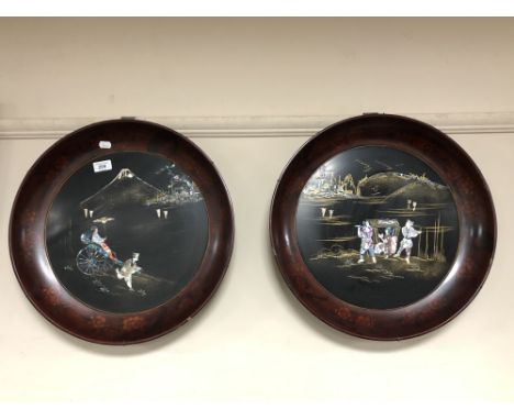 A pair of early 20th century Japanese Shibayama mother of pearl inlaid circular plaques in lacquered frames depicting figures