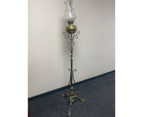 An ornate brass oil standard lamp with etched frosted glass shade and brass reservoir 