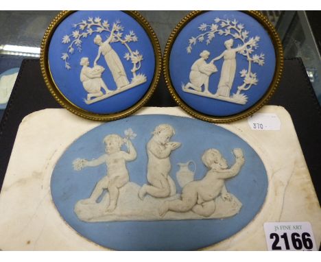 An antique oval blue jasperware plaque of playful putti mounted on a white marble slab and a pair of blue jasperware tie back