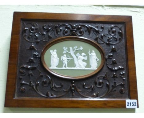 An antique green Jasper ware oval plaque of classical figures with Cupid. Framed in carved walnut panel size over all 27.5cm 