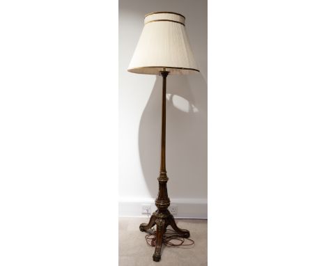 An Edwardian walnut standard lamp, with turned column to carved downswept and scroll footed tripod base, with foliate gilt br