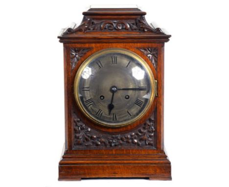 A GERMAN MAHOGANY STAINED AND CARVED OAK MANTLE CLOCK WITH SILVERED DIAL AND BRASS GONG STRIKING MOVEMENT, 34CM H, CIRCA 1910