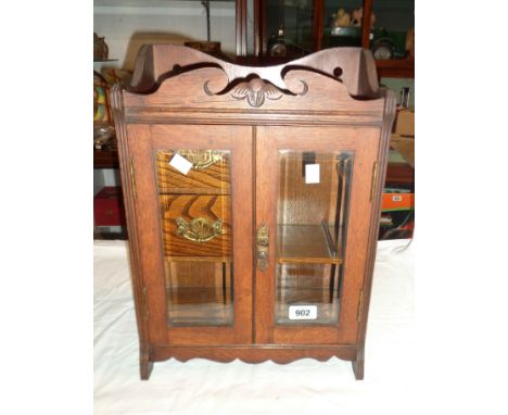 An Edwardian oak smoker's cabinet with two doors and pipe rack enclosed a pair of bevelled glass doors