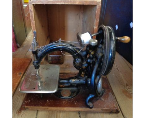 An antique Willcox and Gibbs sewing machine of hoop form with original printed tin toolbox, in original wooden box