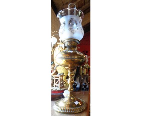 A brass oil lamp of column form with Duplex double burner, clear chimney and frosted shade