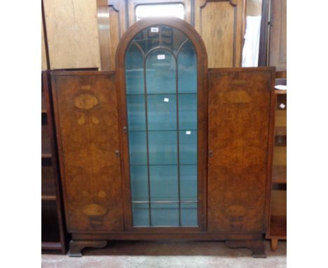 A 1.22m Art Deco walnut break dome-top cabinet with glass shelves enclosed by a central glazed panel door and flanking book m