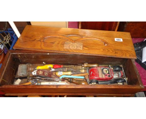 An old wooden slide top box containing a quantity of collectable tools and other items including vintage kitchen implements, 