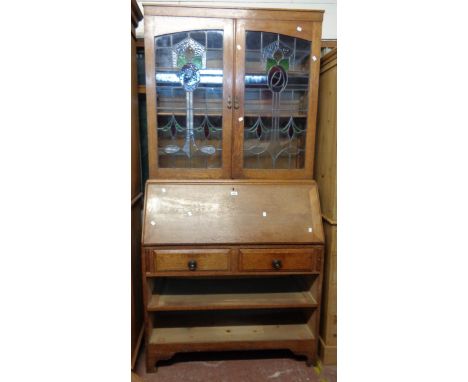 A 1.07m early 20th Century oak bureau/bookcase with decorative leaded glazed panel doors to top over a part fitted interior w