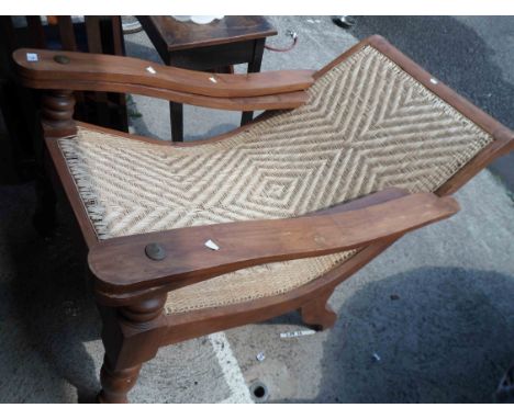 A vintage teak plantation style chair with woven panel seat and fold-out leg rests